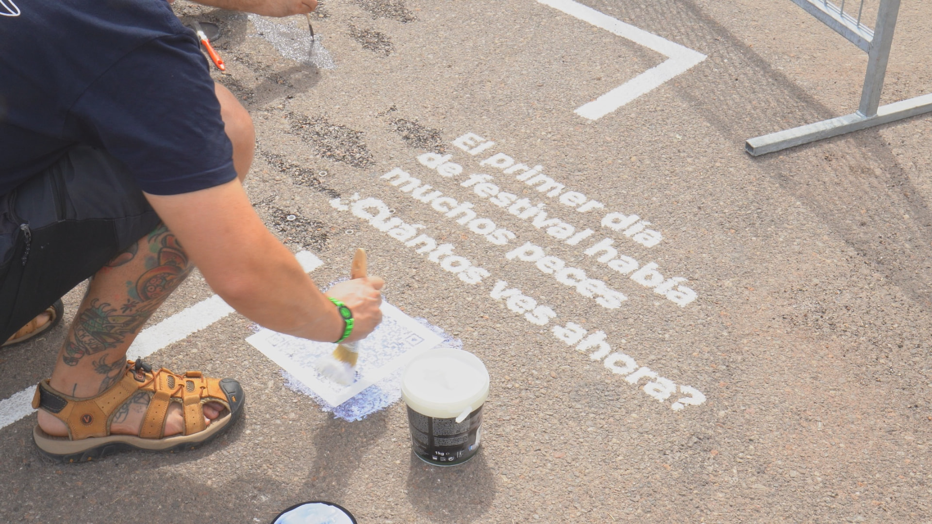 Voluntario pintando con plantilla los mensajes de la instalación en el suelo del recinto