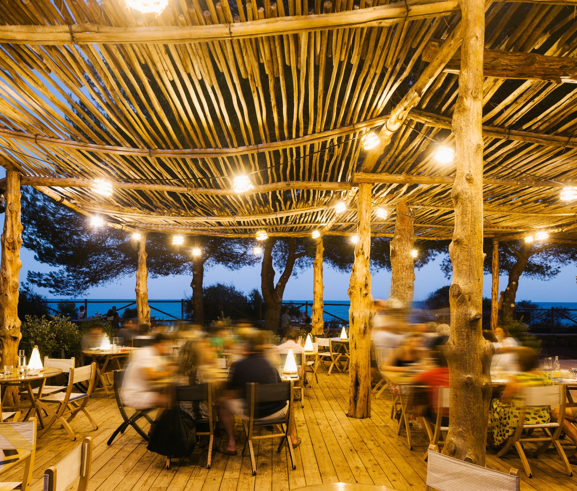 Cena al atardecer bajo la pérgola de cañas de Bosque Masía Bellver, con el mar al fondo