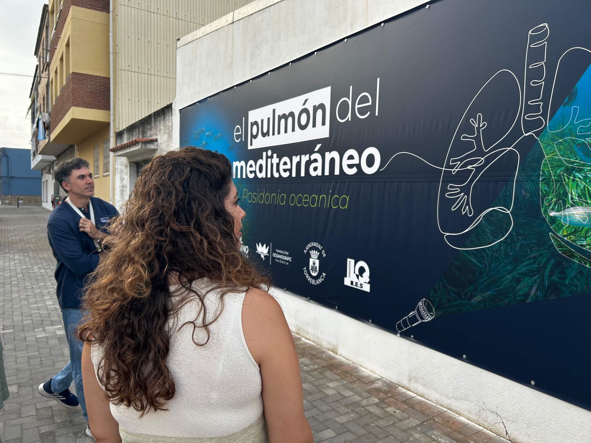 Dos personas observando la lona de “El Pulmón del Mediterráneo” instalada en Torreblanca